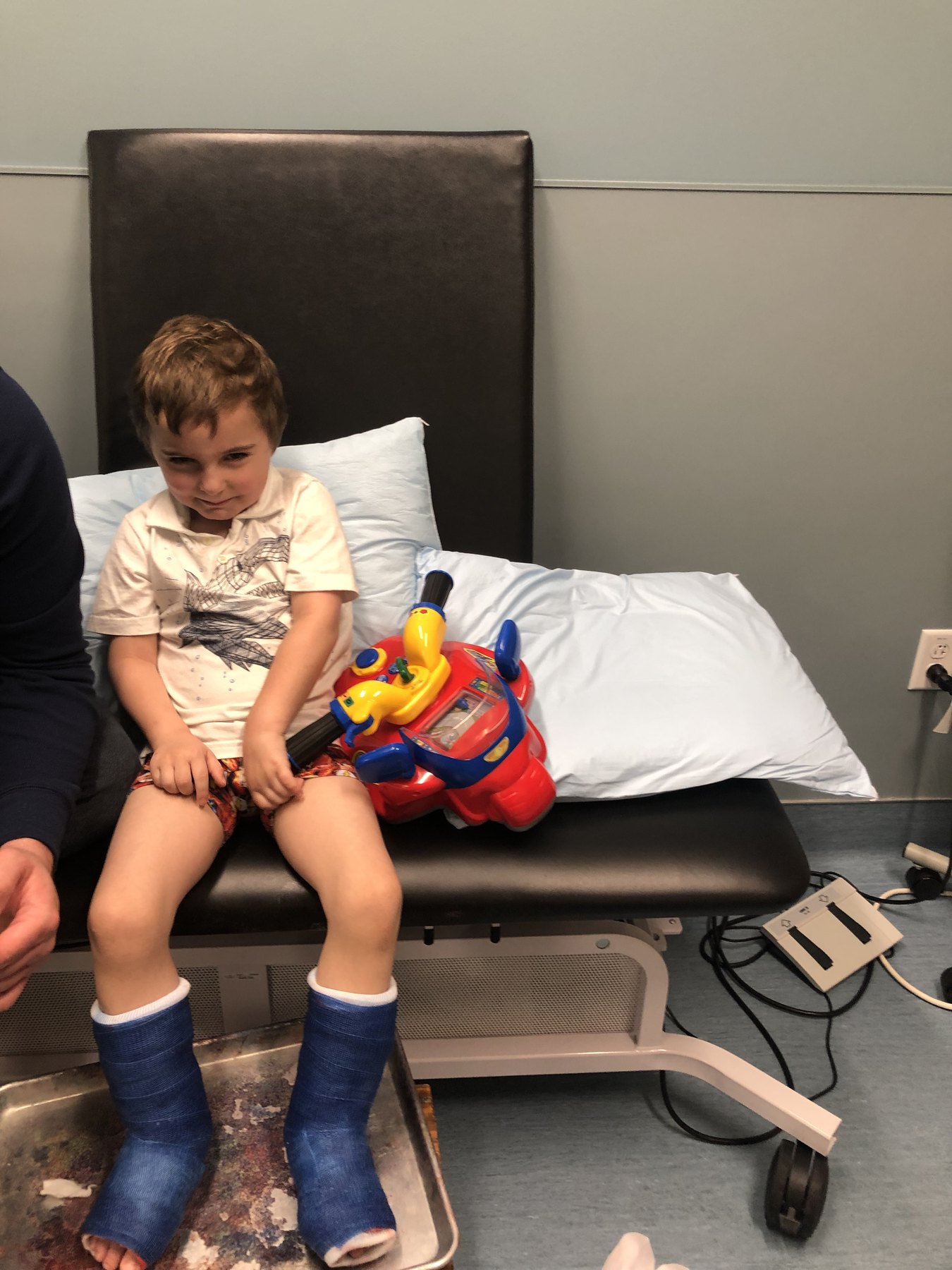 Jack as a young child wearing blue lower-leg casts in an exam room.